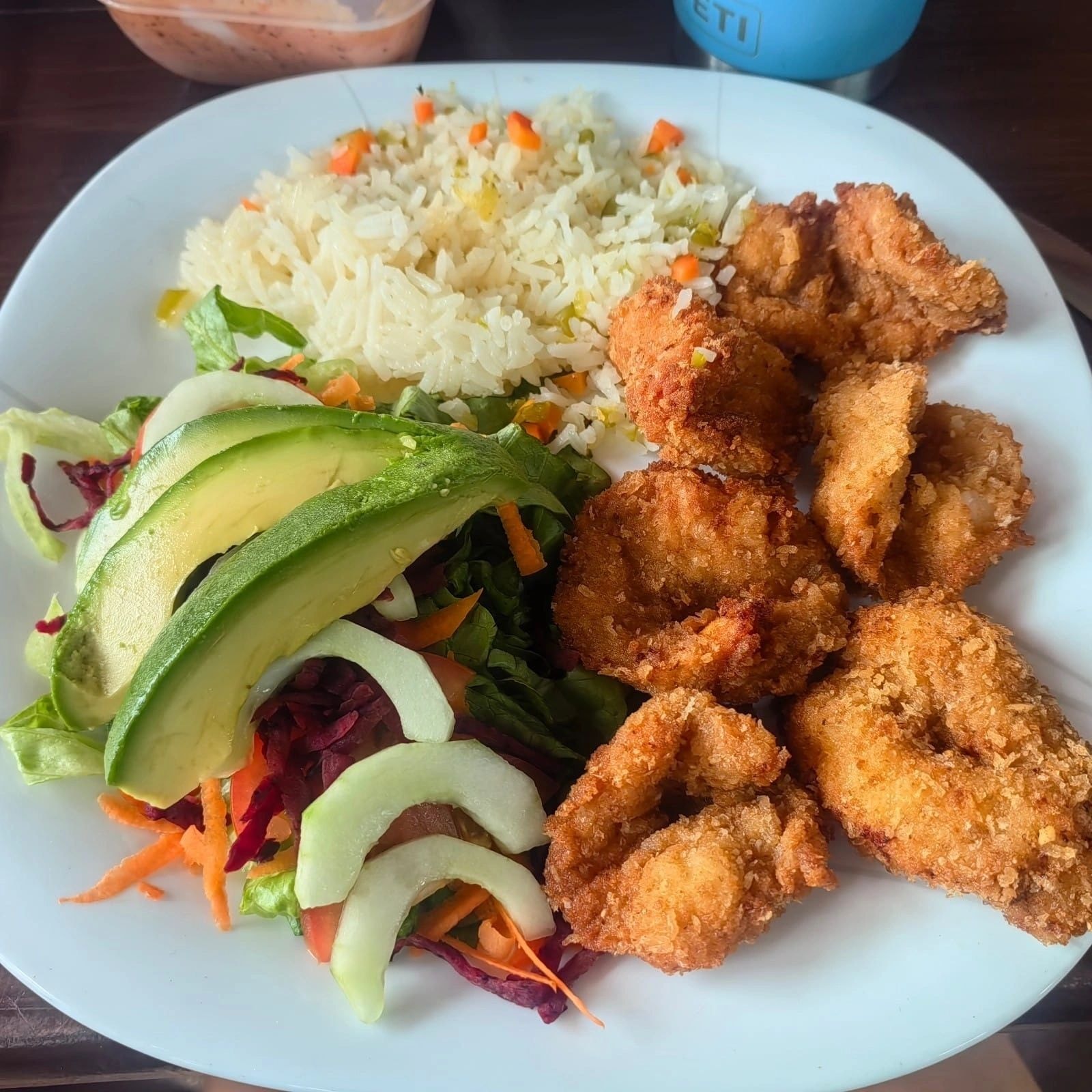Plated shrimp dish with salad and rice